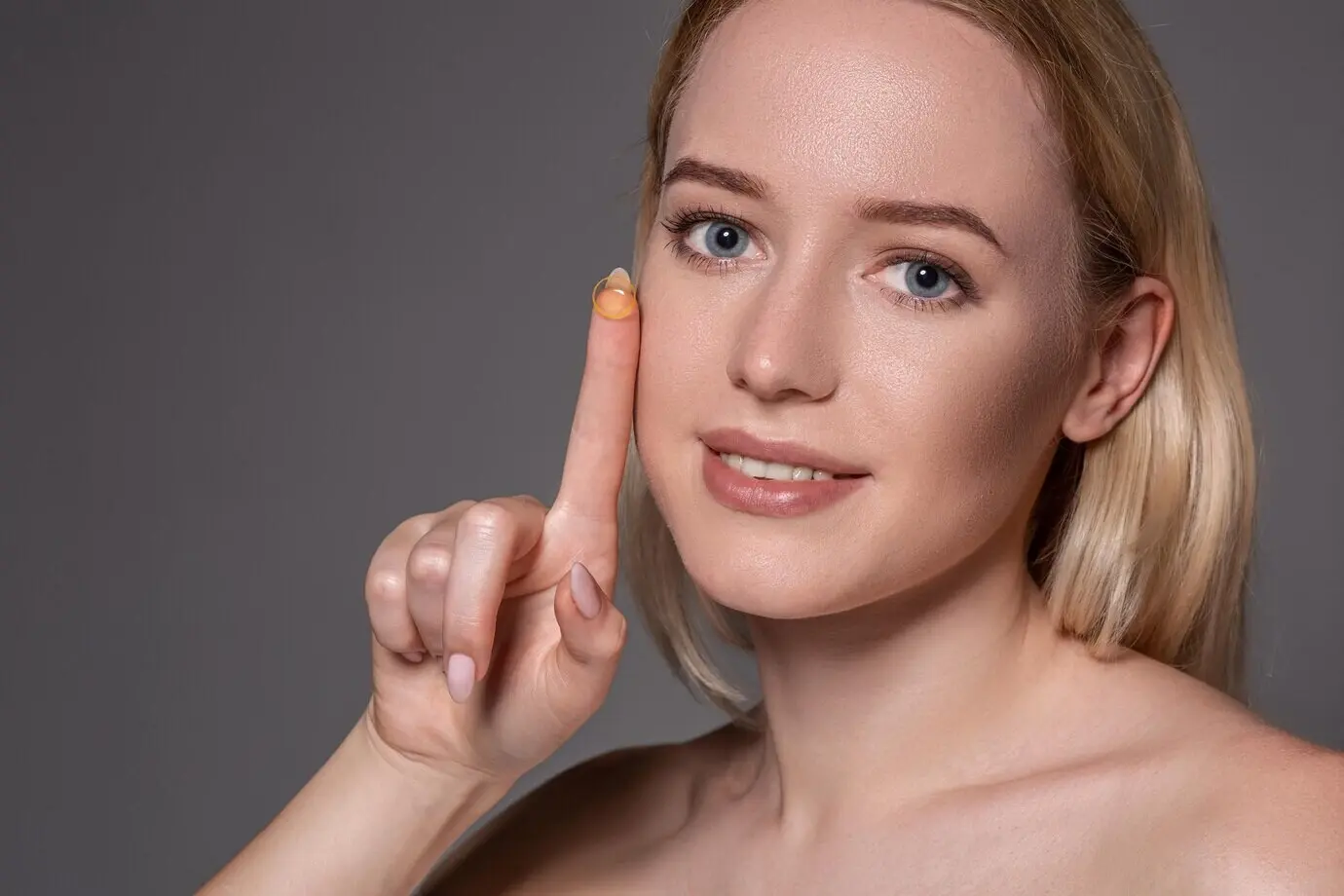 Young woman with a contact lens on her index finger, with copy space. Close-up of a healthy, beautiful woman about to insert a contact lens. Eyesight and ophthalmology theme.